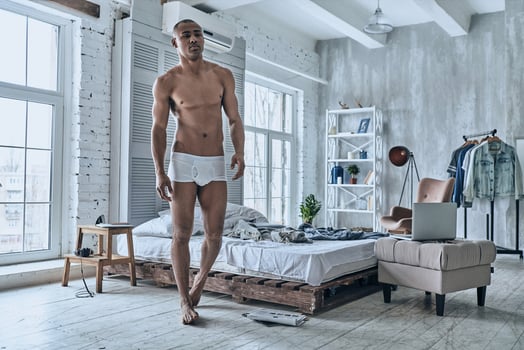 Starting new day. Full length of handsome young African man looking away while walking in the bedroom at home photo