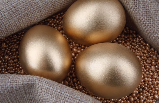 Three golden eggs on gold sand. photo