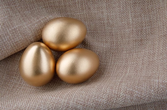 Three golden eggs on a background of tissue. photo
