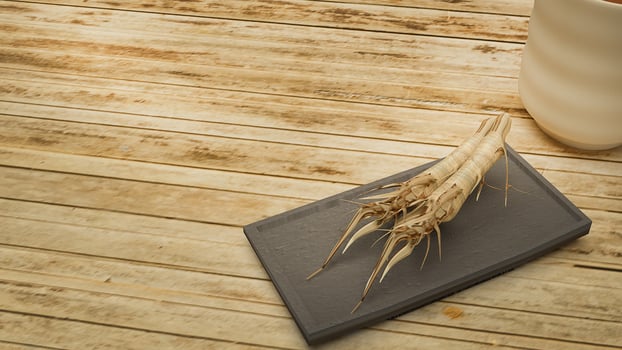 ginseng 3d rendering in black plate on bamboo table  for medical content. photo