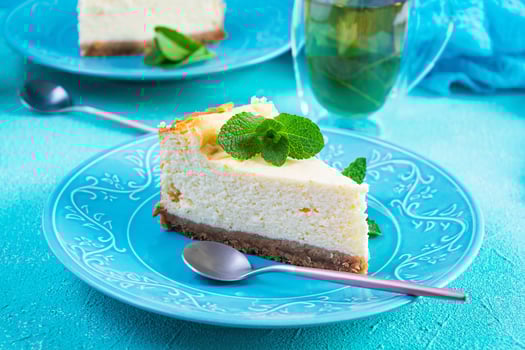 Sliced cheesecake. Delicious sweet cheesecake with mint tea on blue background photo
