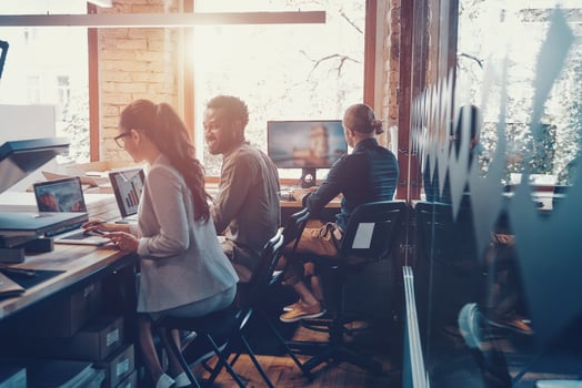 Group of young modern people in smart casual wear communicating and using modern technologies while working in the office photo