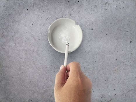 smoking a cigarette, cigarette in hand, ashtray on cement background photo