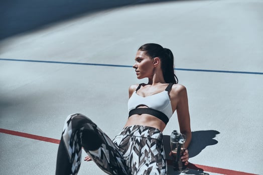 Healthy habits. Top view of young woman in sports clothing relaxing while lying on the running track outdoors photo