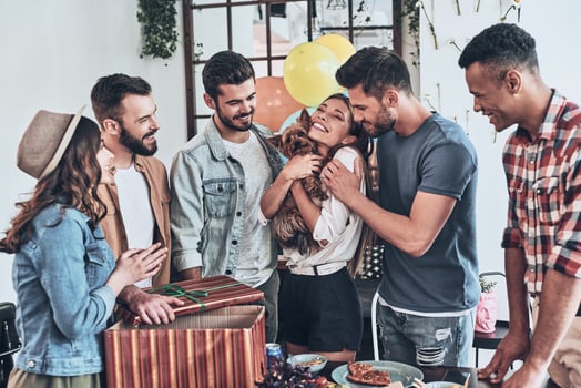 Best birthday surprise. Happy young woman holding a puppy and smiling while her friends standing around photo