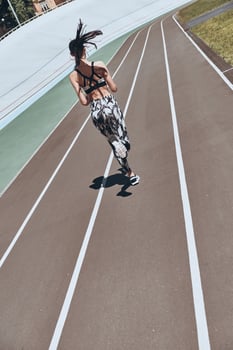 Ready to overcome any obstacle. Full length rear view of young woman in sports clothing jogging while exercising outdoors photo