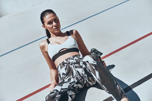 Towards the healthier lifestyle. Top view of young woman in sports clothing resting while lying on the running track outdoors photo