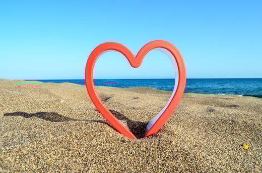 Red plastic heart on the beach photo