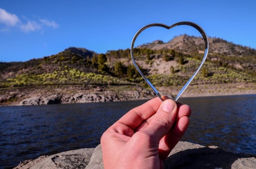 Hand holding a small metal heart photo