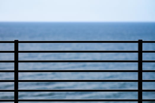 Fencing on observation deck, blue sea background, protection of tourists from falling off cliff photo