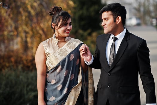 Elegant and fashionable indian friends couple of woman in saree and man in suit walking outdoor and holding hands. photo