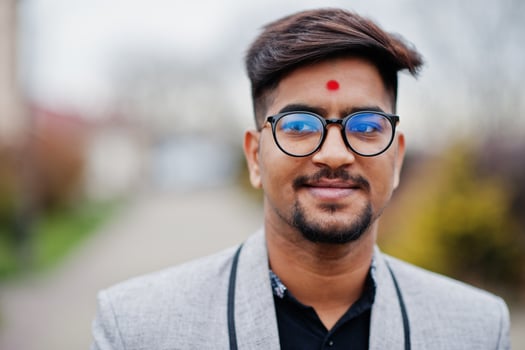 Close up head of stylish indian man with bindi on forehead and glasses, wear on suit posed outdoor. photo