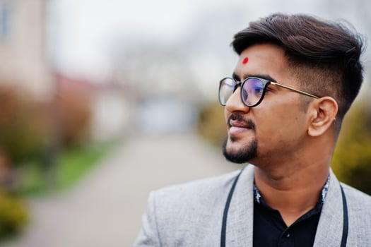 Close up head of stylish indian man with bindi on forehead and glasses, wear on suit posed outdoor. photo