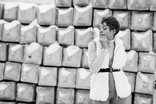 African american woman in red pants and white fur coat jacket posed at winter day against snowy stone background. photo