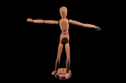 wooden mannequin with arms outstretched on a black background photo
