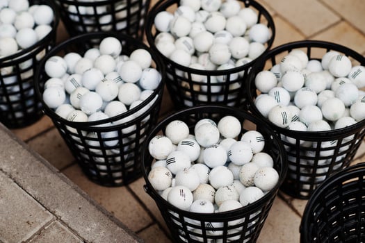 Golf balls in a baskets on pavement. photo