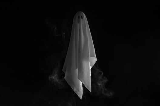 Partial focus of white ghost sheet flying in dark background with smoke. Halloween scary concept. photo