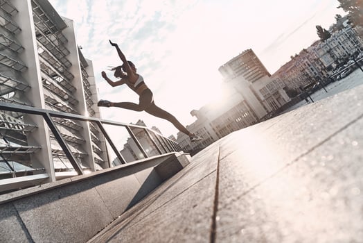 Long jump. Full length of modern young woman in sports clothing jumping while exercising outdoors photo
