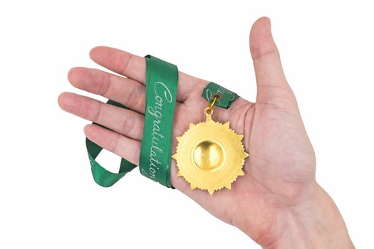 Hand holding Gold medal with green ribbon on white background photo