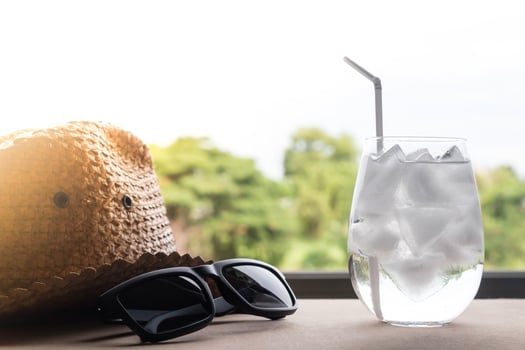 Glass of water with ice cubes, hat and sunglasses on the table. photo