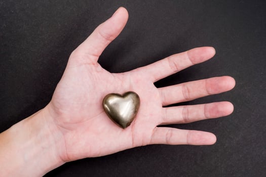 Male hand holding Golden heart on black background photo