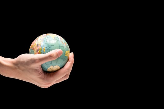 Male hand holding globe on a black background. Free space for text photo