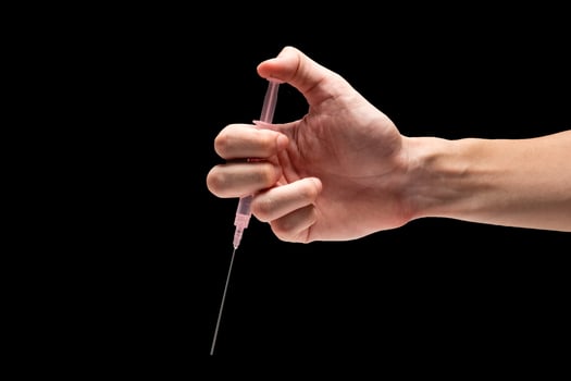 Male hand holding medical tool syringe on a black background. photo