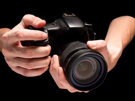 Male hand holding a digital camera on a black background. photo