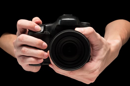 Male hand holding a digital camera on a black background. photo