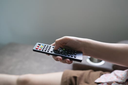 Close up Television remote control in young woman pink shirt hands pointing to tv set and turning it on or off. select channel watching tv on sofa at home in the living room relax. photo