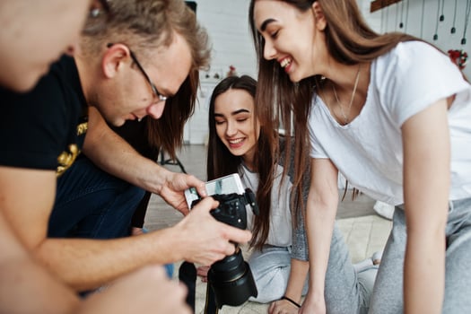 The team of photographers showing pictures on screen of camera for twins models girls on studio. Professional photographer on work. photo