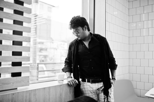 Stylish indian man in sunglasses stay near window with cup of coffee on fast food cafe. photo