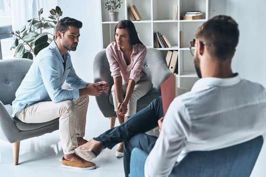 Speak out. Young married couple talking while sitting on the therapy session with psychologist photo