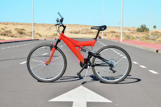 a red bicycle is parked on the road photo