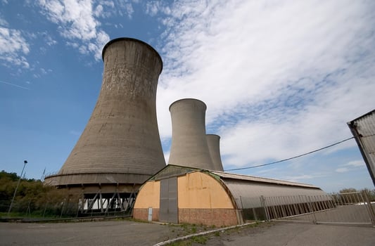 two cooling towers sit next to a building photo