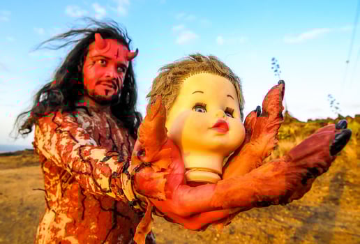 a man dressed as a devil holding a doll photo