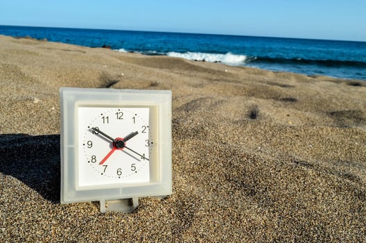 a clock on the beach with the ocean in the background photo