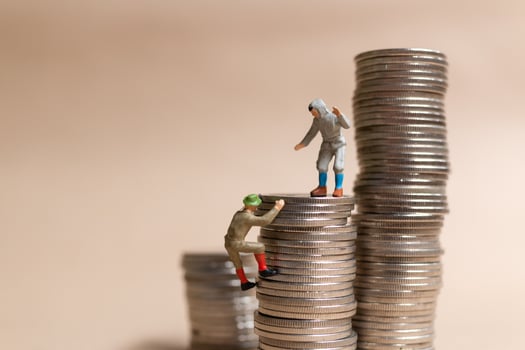Miniature people Mountain climber ascending the coin stack photo