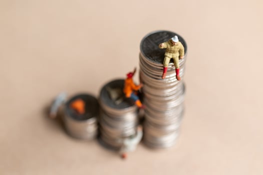 Miniature people Mountain climber ascending the coin stack photo
