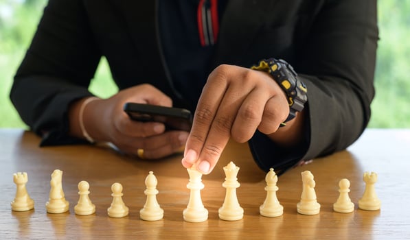 Businessman hands in black suite sitting and pointing chess king on vintage table meaning of planning and strategy. Decision and achievement goal concept. photo