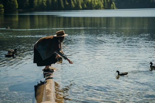 Young beautiful girl feeds a duck by the lake photo