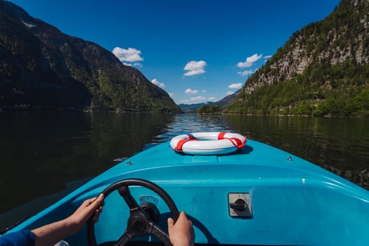 Handsome young guy controls a motorboat on a mountain lake photo