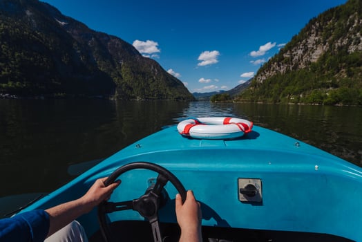 Handsome young guy controls a motorboat on a mountain lake photo