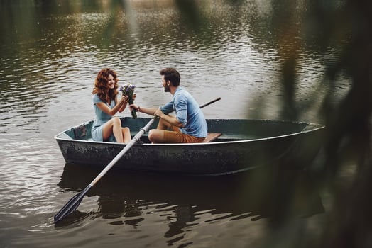 Flowers for her. Handsome young man giving bouquet to his beautiful girlfriend while enjoying romantic date on the lake photo