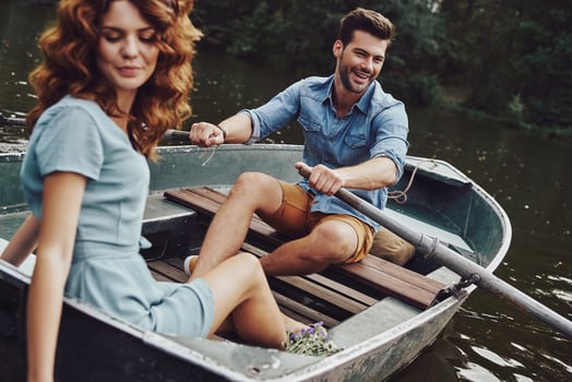 Simple joy of loving. Beautiful young couple enjoying romantic date and smiling while rowing a boat photo