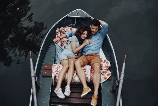 Enjoying weekend together. Top view of beautiful young couple embracing and smiling while lying in the boat photo