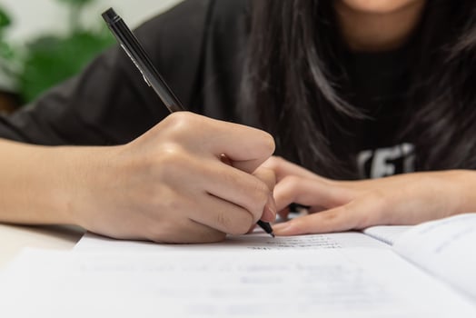 Asian student girl is writing homework and reading book at desk photo