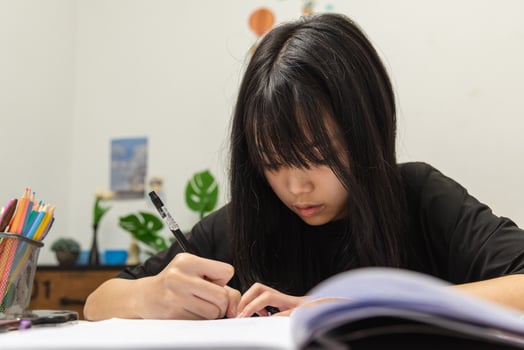 Asian student girl is writing homework and reading book at desk photo
