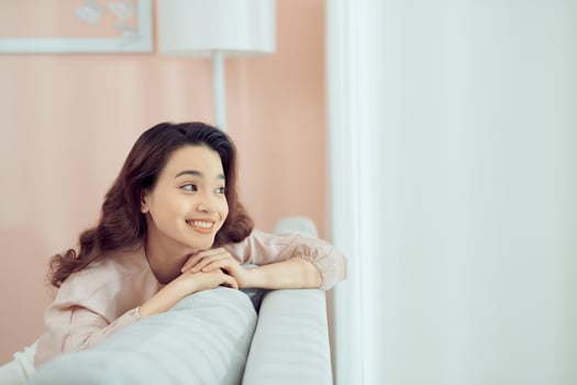 Smiling relaxed attractive woman wearing glasses sitting on a sofa looking back over her shoulder photo