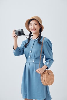 Young Asian woman holding a vintage camera on white background photo